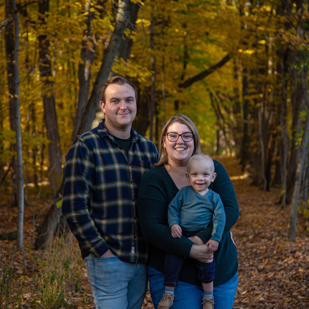 Mom, dad, baby boy portrait in wooded area.